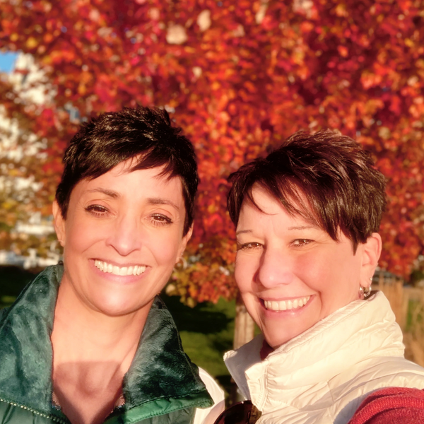 Angela and Christine, co-owners of AHA Moments standing in front of a beautiful autumn maple tree