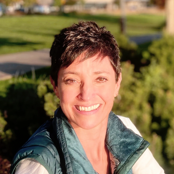 A professional photograph of a Hispanic woman named Angela Lopez sitting in the sunlight.