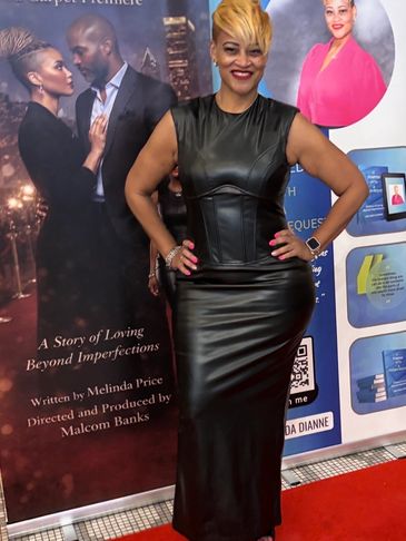 A woman poses confidently on a red carpet in a sleek black leather dress.