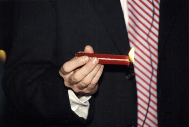Hand holding a lit red candle.
