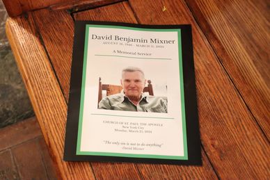 Memorial service program for David Benjamin Mixner laid on a wooden surface.