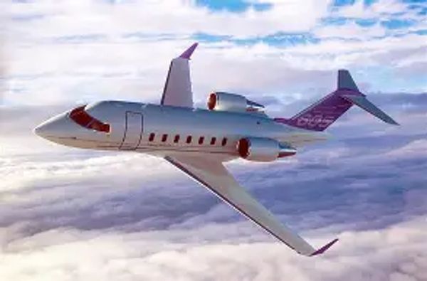A sleek private jet flying above the clouds during sunset.