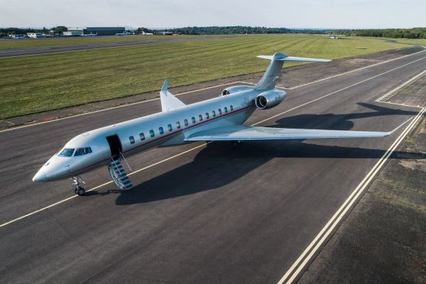 Private jet parked on runway with open door and stairs.