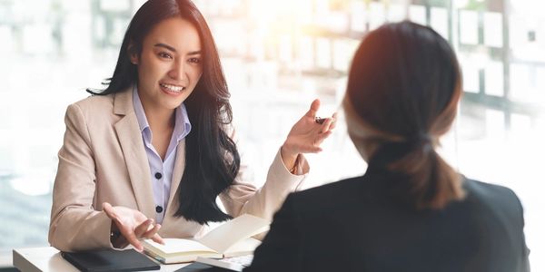 Two women engaged in a professional business discussion at a table.