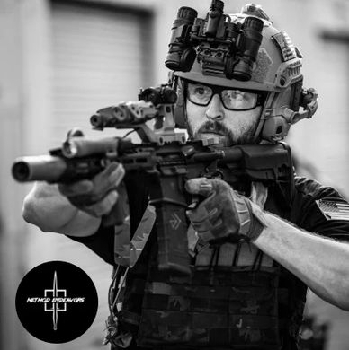 Tactical operator aiming a rifle with night vision gear in black and white.