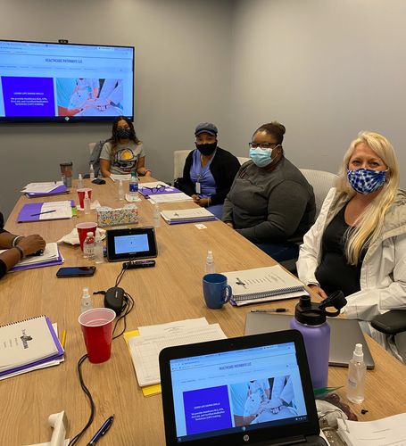 A team member sitting on the room wearing masks and looking on the camera