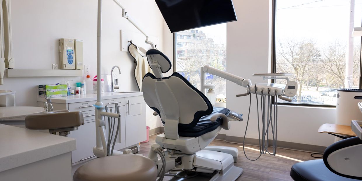 Modern dental clinic with a dental chair and equipment by a large window.
