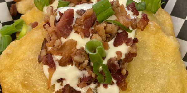 Fried potato pancakes topped with sour cream, bacon bits, and green onions.