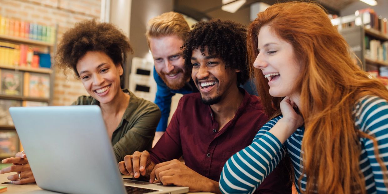 Group of people smiling and looking at a laptop screen