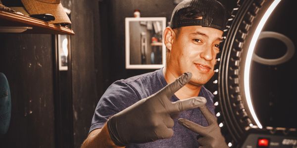 Man wearing gloves and a cap posing with a peace sign in a dimly lit room.