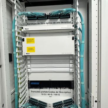 Rack with organized high-density fiber optic trays and prefabricated fiber optic trunks.