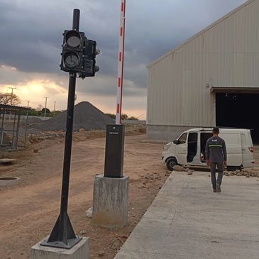 A man walks near a white van at a construction site with a traffic signal and barrier.