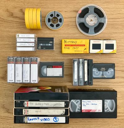 Vintage tapes and film reels arranged on a wooden surface.