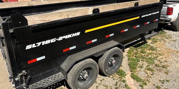 Black Southland trailer with dual axles parked on gravel and grass.