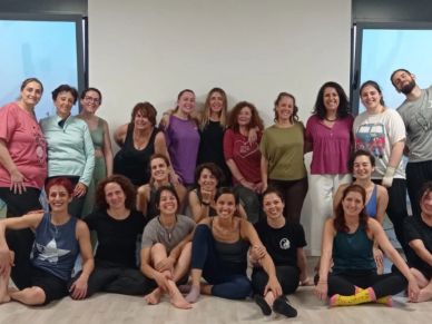 A group of smiling people posing together in a bright room.
