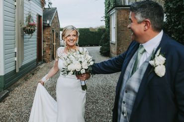 Groom leading his new bride by the hand down a stoney path outside Friern Manor 