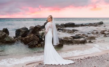 A bride standing on Southend sea front holding her flowers looking over her shoulder at the camera. 