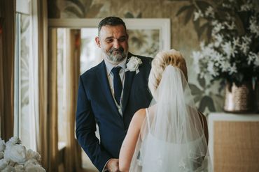 An image looking over a brides shoulder at the love of the groom looking at her