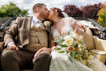 Bride & groom sharing a kiss in their wedding car outside the beautiful Essex Venue Little Channels