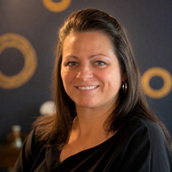 Smiling woman with dark hair and hoop earrings.