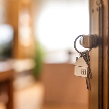 Key with house-shaped keychain in door. Symbolizing homeownership.