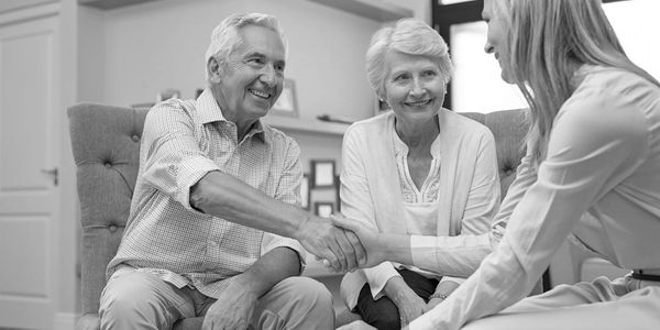 Man shaking hands with a young woman while another woman looks on 