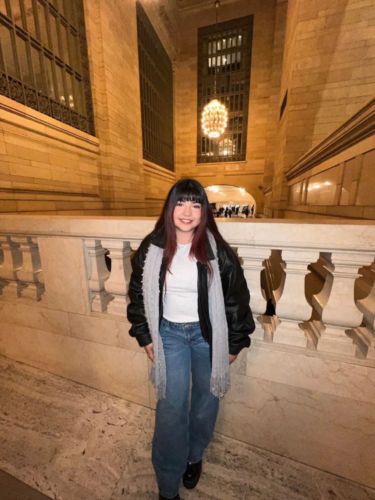 Stack of books next to pencils in a holder and a camera.