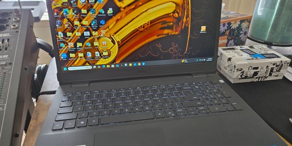 Dell Inspiron laptop on a desk with a saxophone wallpaper.