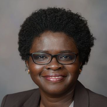 Portrait of a smiling woman with glasses and short curly hair.