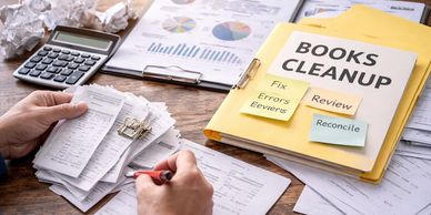 Person reviewing financial documents with a calculator and folders labeled 'Books Cleanup'.