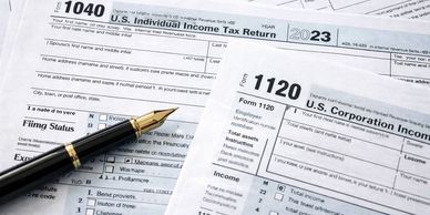 U.S. tax forms 1040 and 1120 with a fountain pen.
