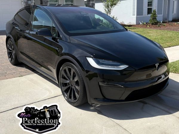 Sleek black Tesla Model X parked on driveway after detailing.