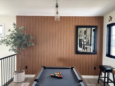 Modern game room with pool table and wood accent wall.