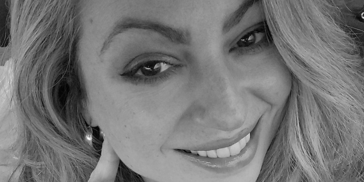 Close-up black and white portrait of a smiling woman with wavy hair.