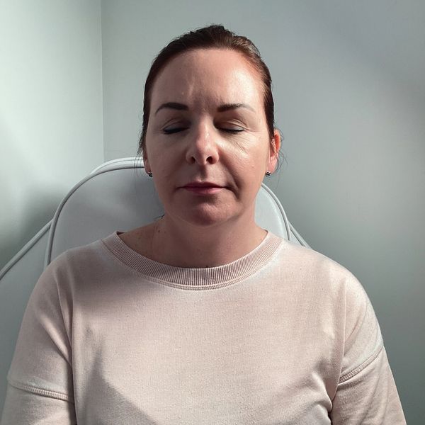 Woman with closed eyes sitting calmly in a light-colored room.