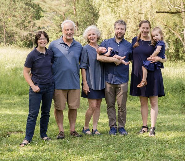 A multi-generational family posing outdoors on a sunny day.