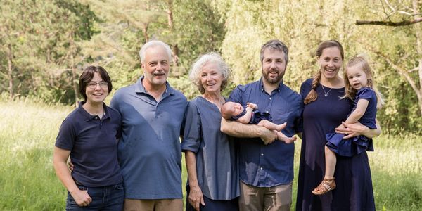 A multi-generational family posing outdoors on a sunny day.