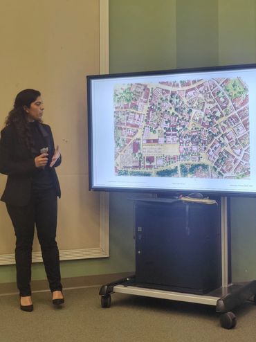 Woman presenting a detailed map on a large screen.