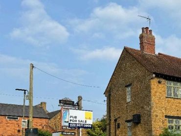 Old brick pub building with a 'For Sale' sign.