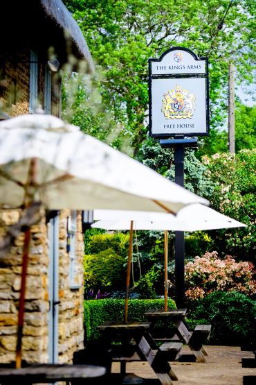 Outdoor seating at The King's Arms pub with white umbrellas.