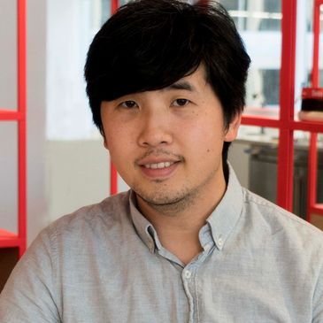 Young man sitting at a table in a modern office space.