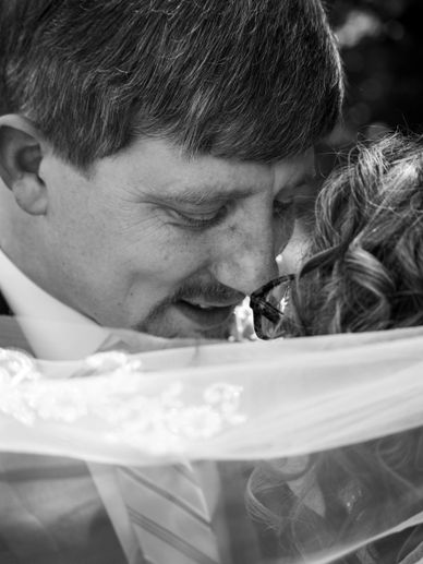 Intimate black-and-white close-up of a couple sharing a tender moment under a veil.