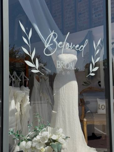 Elegant white bridal gown displayed behind a glass door.