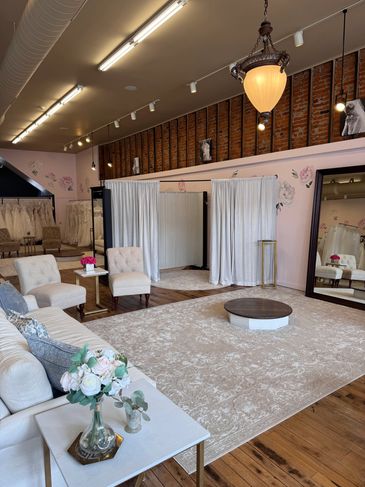 Elegant bridal boutique fitting room with seating and large mirror.