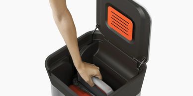 Person disposing plastic bottle in recycling bin.