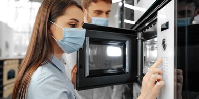 Woman wearing mask using microwave.