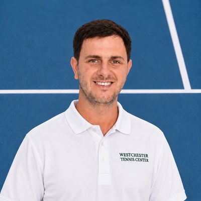 Man in a white polo on a tennis court.