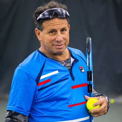 Man in blue tennis shirt holding a tennis ball and racket.