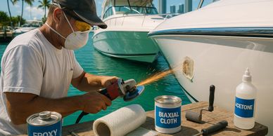 Man repairing boat hull with power tool and safety mask.
