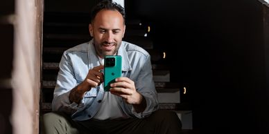 Hombre sonriendo usando un teléfono móvil.